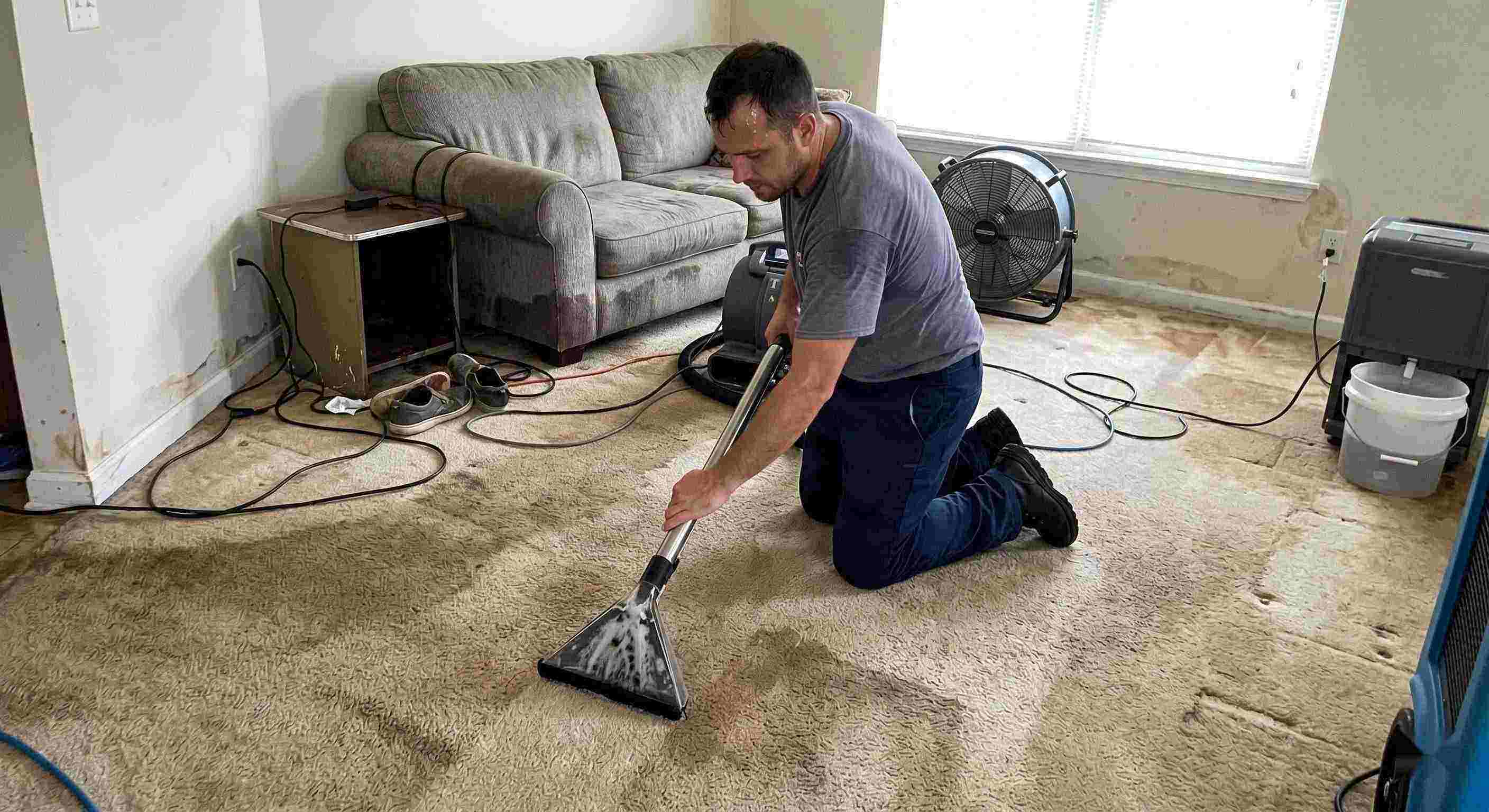 Technician performing carpet water extraction in a residential home using professional equipment after water damage in Rochester