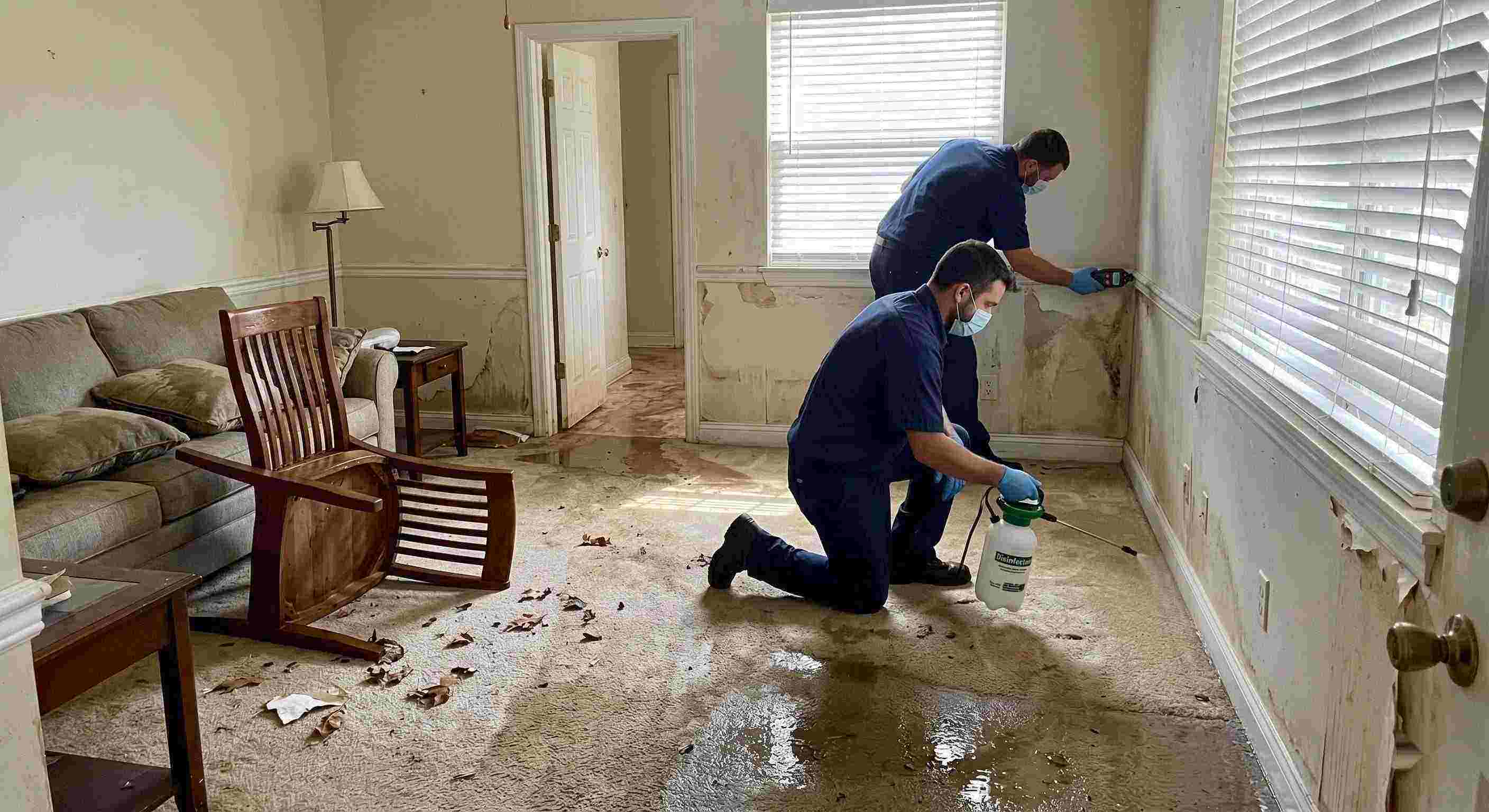 Technicians performing flood disinfection after water damage inside a home in Rochester, ensuring wet floors, damp walls, and household items are sanitized safely.